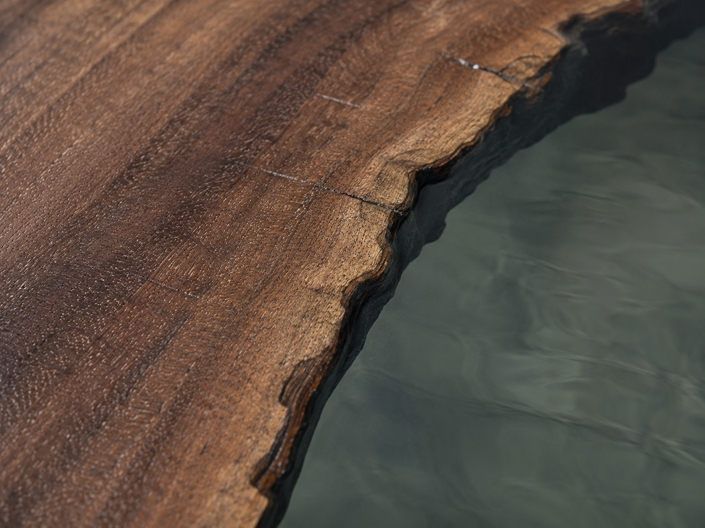 Irregular walnut edge meeting a clear resin surface